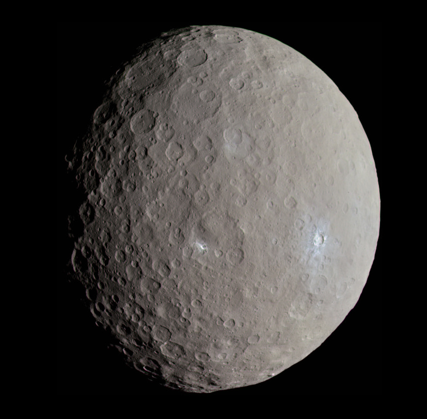 The asteroid Ceres, roughly spherical with a grey surface, many craters, some of which reveal white subsurface water ice.