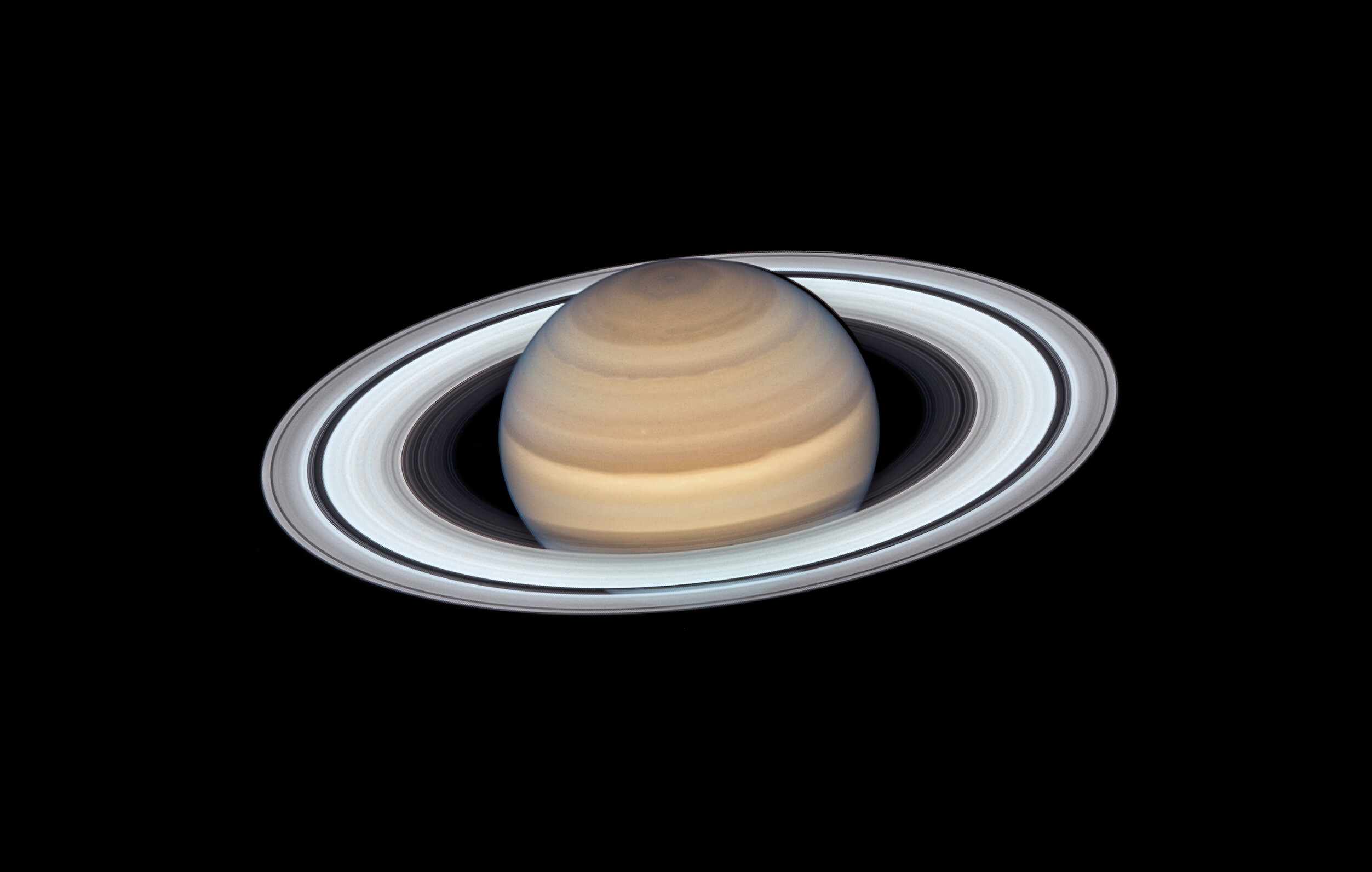 The planet Saturn with pale brownish cloud ribbons and its thin and extended greyish rings