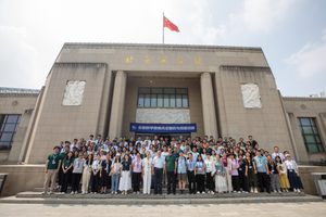A group of people stand in-front of a building on-top of which flies the flag of the PR China
