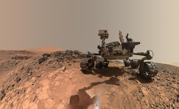 The NASA Mars rover Curiosity stands on a hill on Mars.