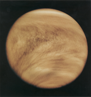 Venus as a circular disk against a dark background, with visible patterns and streaks in its atmosphere.