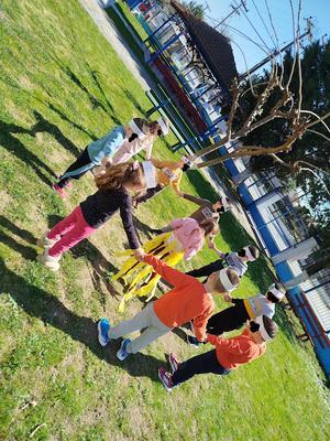 Nine children stand holding hands in a circle around another child dressed as the Sun