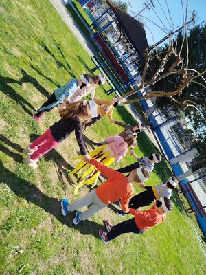 Nine children stand holding hands in a circle around another child dressed as the Sun