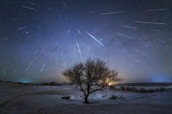 Bright streaks created by meteors radiate away from a point in the starry sky