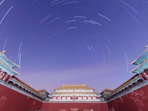 A traditional Chinese building. Above the streaks of stars form a circular pattern around the north star.