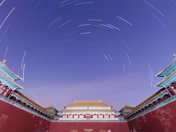 Un edificio tradizionale cinese. In alto le tracce delle stelle formano un disegno circolare intorno alla stella polare.