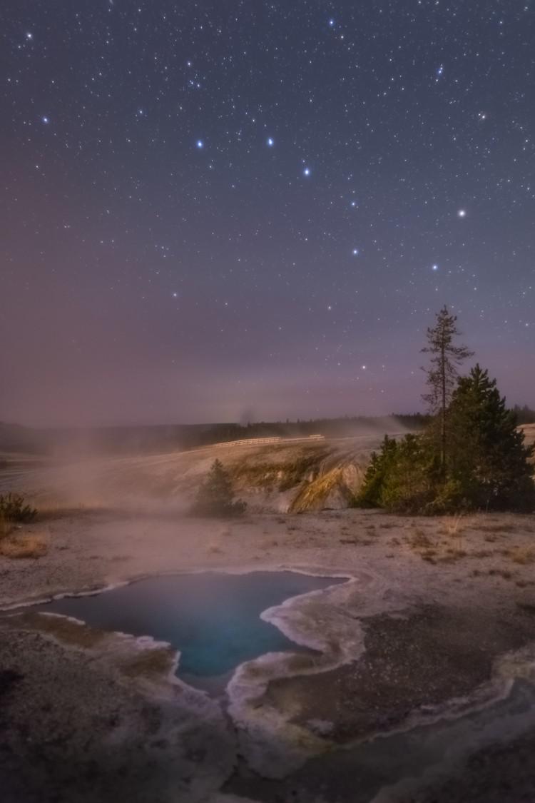 A steaming pool of water with the night sky. The sky shows a bright group of 7 stars in the shape of a pan and handle