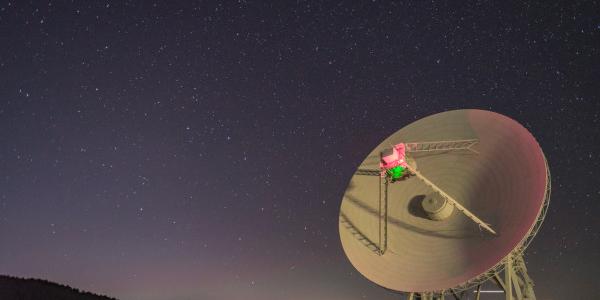 The dish of a radio telescope rotates as the Big Dipper moves in the sky behind.