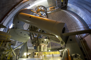 The Hale Telescope mounted inside a large observatory dome, showing its massive optical tube and support structure.