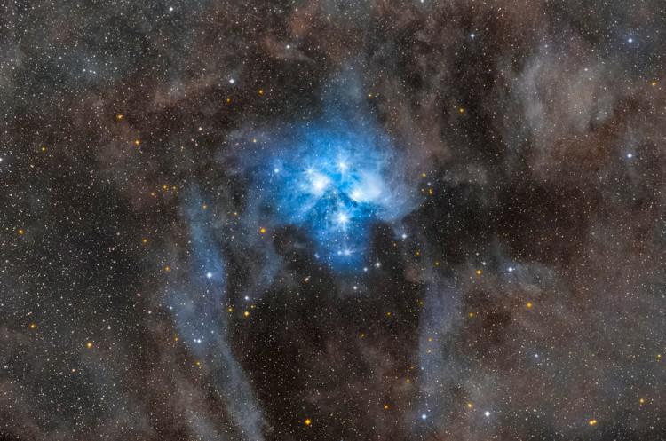 A cluster of brilliant blue stars illuminate the surrounding nebular gas.